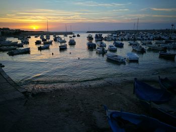 Boats moored at harbor during sunset