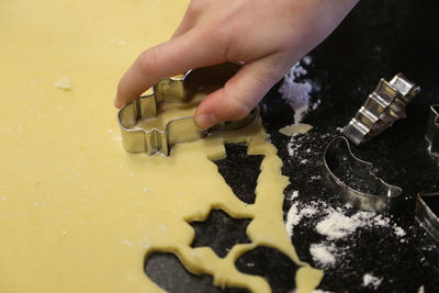 Cropped hand of woman making cookies in kitchen