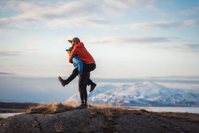 Woman giving man piggyback with mountains behind them