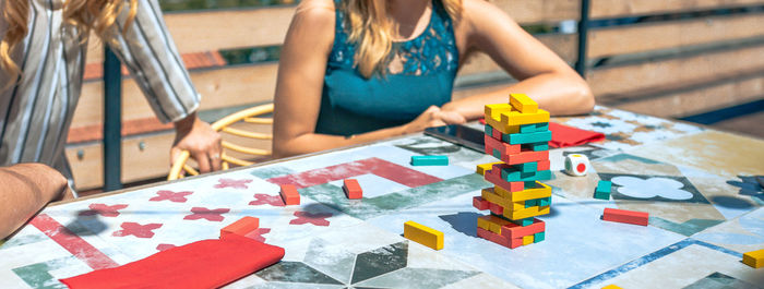 Jenga tower over table with unrecognizable people playing in a rooftop party