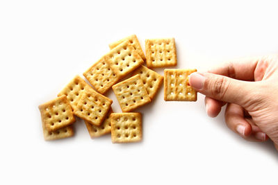Close-up of hand holding cookies against white background