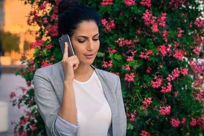 Young woman standing by flowers