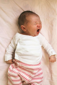 High angle view of baby yawning in bed