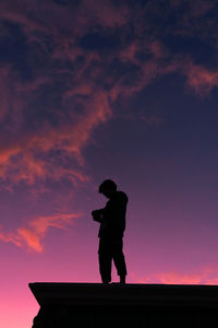 Silhouette man standing against orange sky