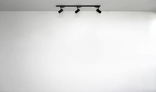 Low angle view of electric lamp hanging against white wall