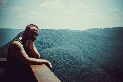 Man sitting by sea against sky