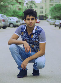 Portrait of young man sitting on road