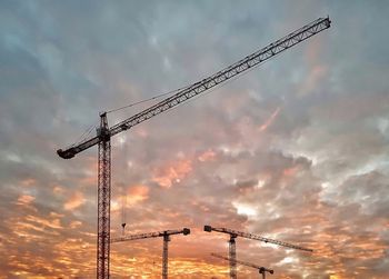 Low angle view of silhouette crane against sky during sunset