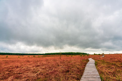 Dirt road on field against sky