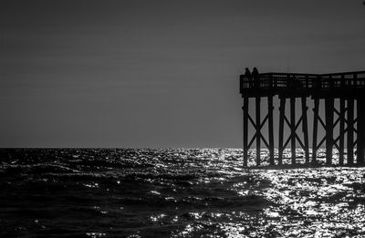 Silhouette pier over sea against sky