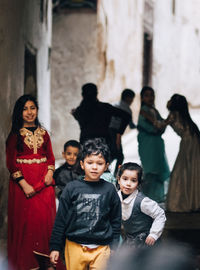 Full length portrait of happy friends standing against blurred background