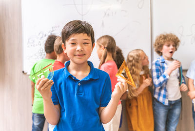 Portrait of cute boy holding ruler in classroom