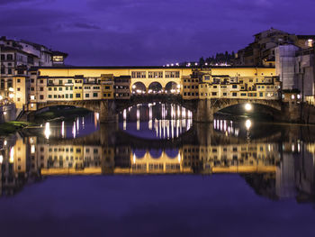 Reflection of illuminated ponte vecchio in river at night