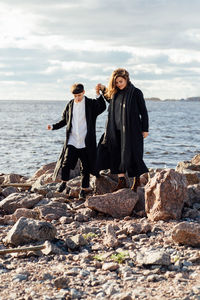 Woman standing on rock at beach against sky