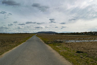 Road amidst field against sky