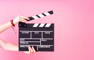 Low angle view of hand holding umbrella against pink background