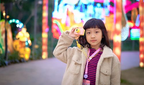 Portrait of happy girl standing in illuminated during winter