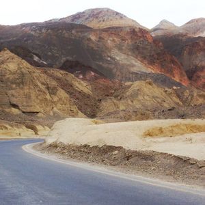 Scenic view of road by mountains against sky