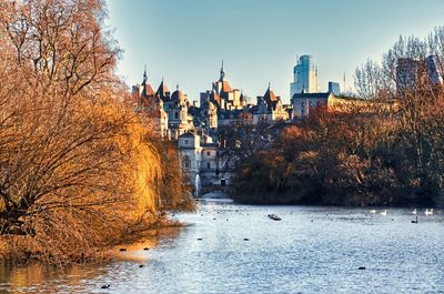 View of buildings by river against clear sky