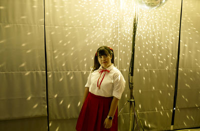 Woman standing against illuminated wall