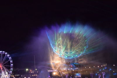 Low angle view of illuminated ferris wheel against sky at night