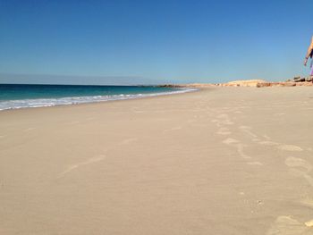 Scenic view of beach against clear blue sky