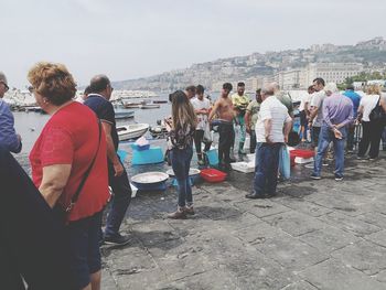 People at beach against sky in city