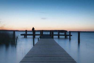 Pier over sea against sky during sunset