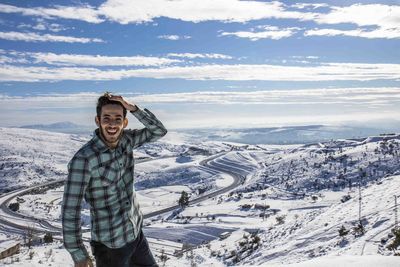 Portrait of smiling man standing on snow covered landscape