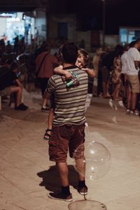 Rear view of people standing on street at night