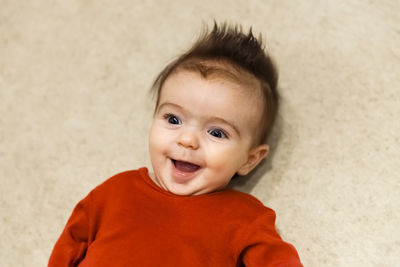 High angle view of cute smiling baby girl lying on bed at home