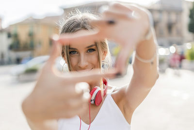 Portrait of smiling teenage girl making a finger frame in the city