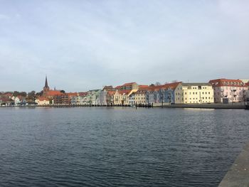 View of buildings at waterfront against cloudy sky