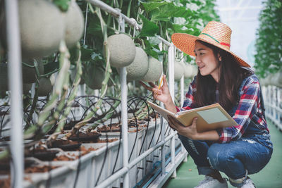 Woman standing by plants at greenhouse