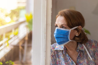 Elderly watches through the window of her house
