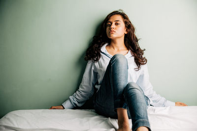 Young woman sitting against wall