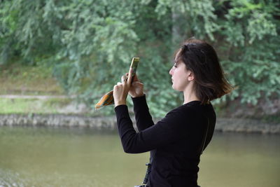 Woman photographing against lake
