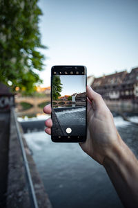 Man photographing with mobile phone against sky