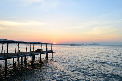 Pier over sea against sky during sunset