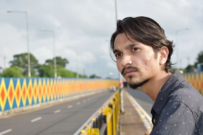 Young man looking away while standing on road