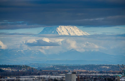 Clouds partially cover mount rainier which towers over the port of tacoma.