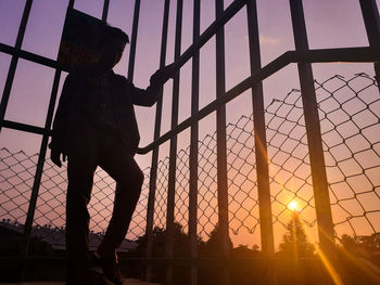 Silhouette man standing against orange sky during sunset