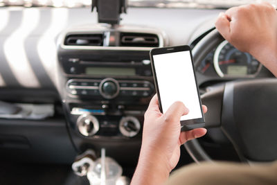 Cropped hand of man using phone while driving car