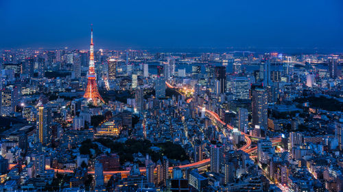 Aerial view of illuminated tokyo tower amidst buildings in city at night