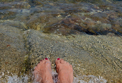 Low section of woman sitting on rock in river