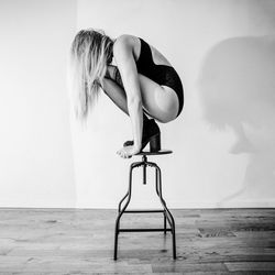 Woman sitting on seat against wall at home