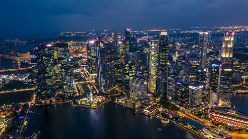 Aerial view of illuminated buildings by river at night