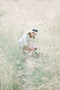 Woman with flower crouching on field