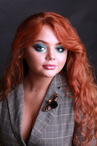 Close-up portrait of beautiful young woman against black background