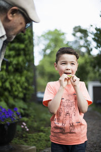 Grandfather looking at grandson holding leaf in back yard